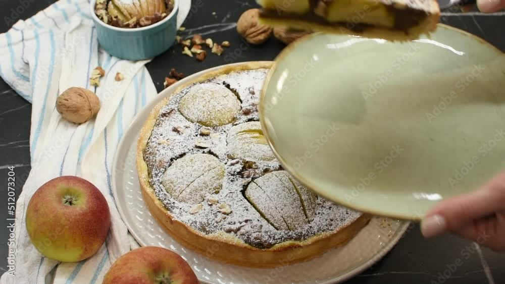 a caucasian woman cuts an apple pie with a large knife with her hands and removes a piece on a plate a caucasian woman cuts an apple pie with a large knife with her hands and removes a piece on a plate