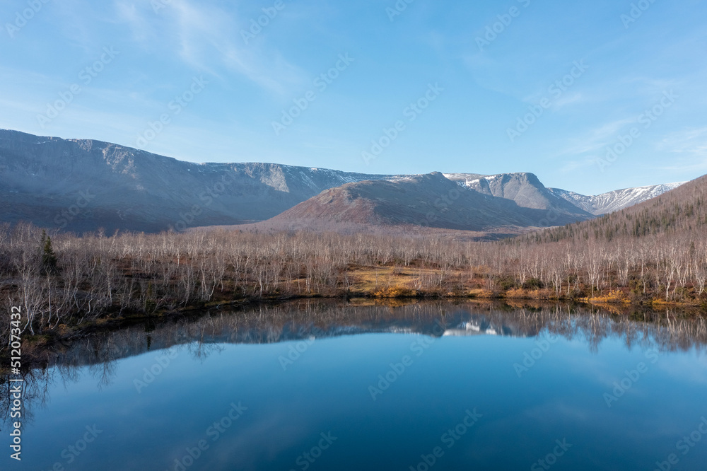 Blue mountain lake on the background snow-capped mountain picks in polar autumn. Landscapes of Northern Nature. Nature regions of Russia. Russian north.
