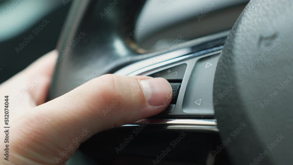Volume up on streering wheel radio control button - man's thumb close up Volume up on streering wheel radio control button - man's thumb close up