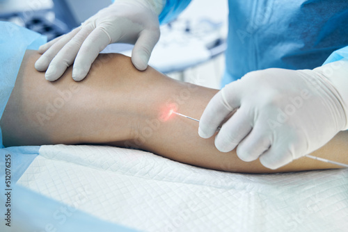 Doctor phlebologist is performing endovenous laser treatment photo