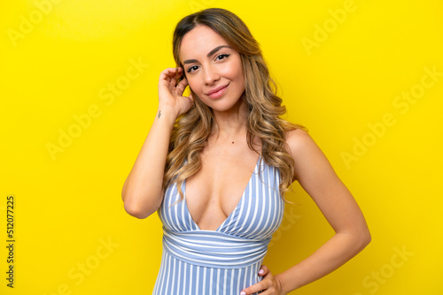Young caucasian woman isolated on yellow background in swimsuit in summer holidays