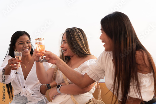 Three seated women toasting with glasses of wine at a party