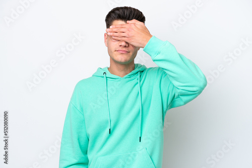 Young handsome caucasian man isolated on white bakcground covering eyes by hands. Do not want to see something © luismolinero
