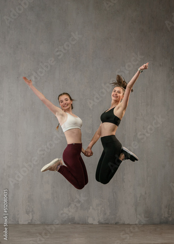 Young happy athlete women are posing, jumping high in studio, copy space.