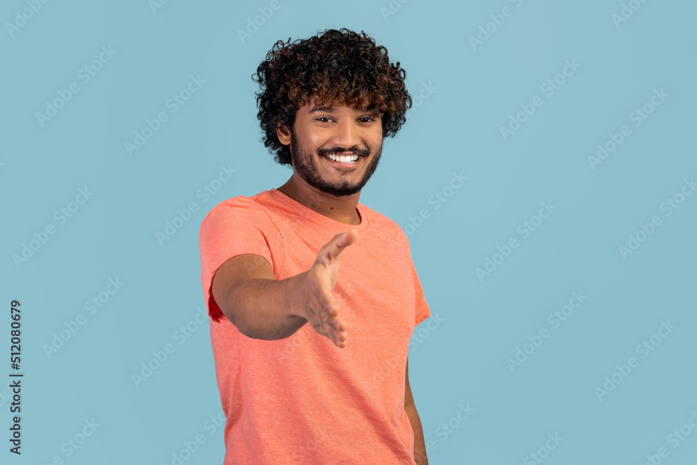 Friendly hindu guy outstretching hand and smiling Friendly hindu guy outstretching hand and smiling