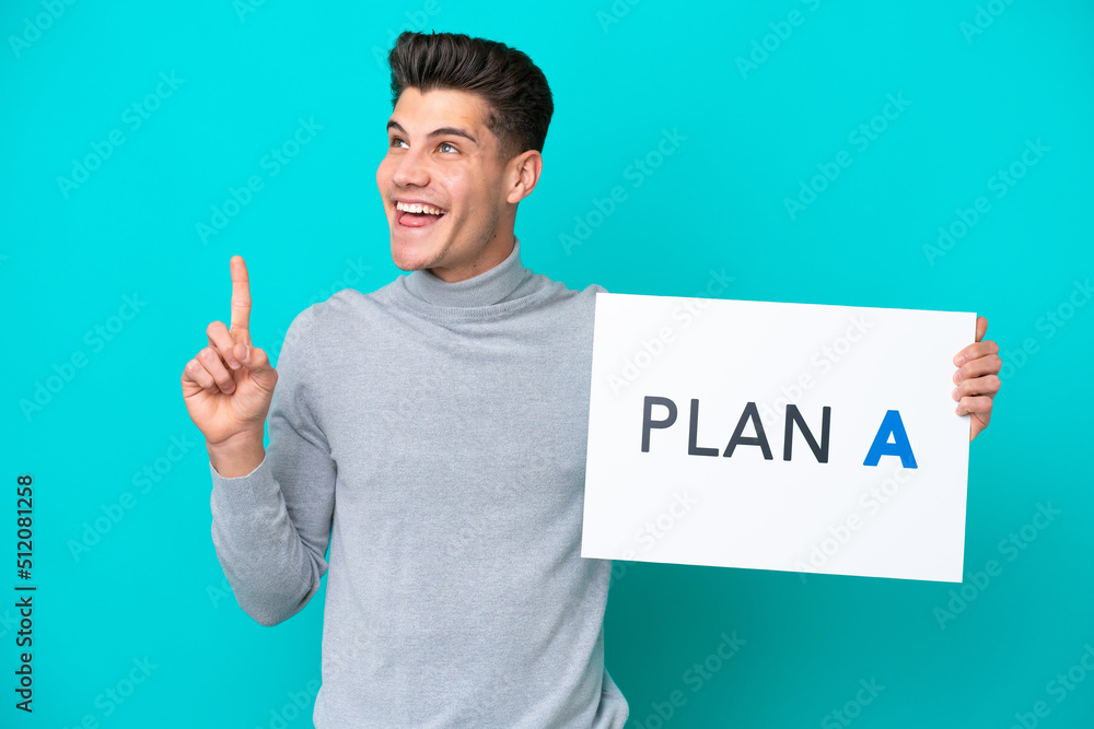 Young handsome caucasian man isolated on blue bakcground holding a placard with the message PLAN A and thinking Young handsome caucasian man isolated on blue bakcground holding a placard with the message PLAN A and thinking