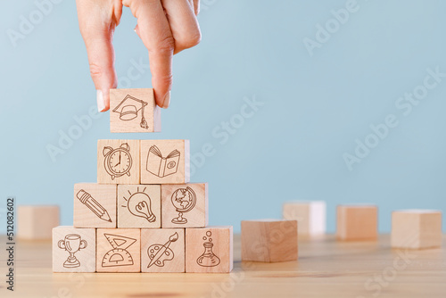 Female hand arranging wood block stacking with elements education icons
