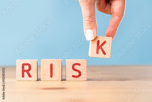 Woman's hand writing the word Risk with wooden cubes