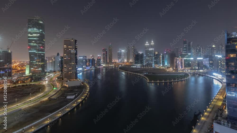 Cityscape of skyscrapers in Dubai Business Bay with water canal aerial night timelapse. Modern panoramic skyline with illuminated towers and waterfront. A center of international business Cityscape of skyscrapers in Dubai Business Bay with water canal aerial night timelapse. Modern panoramic skyline with illuminated towers and waterfront. A center of international business