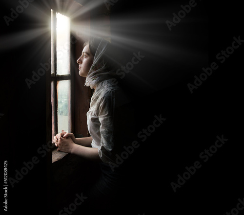 Fotografia Woman praying at the window