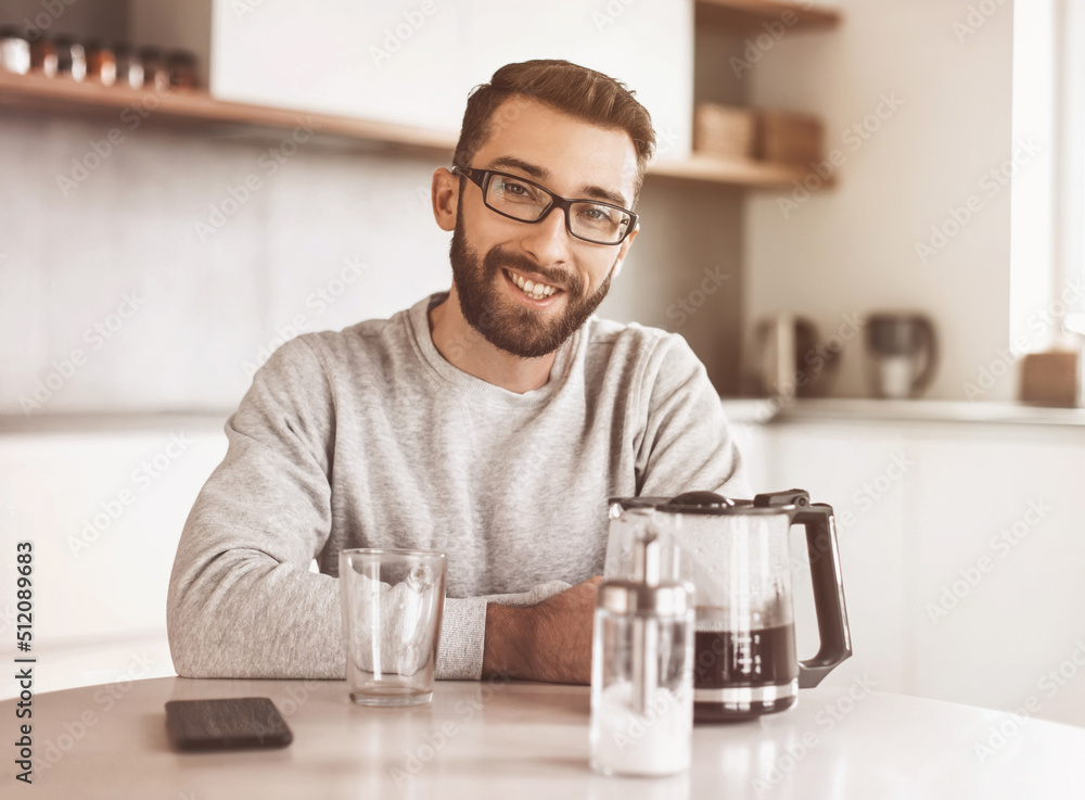 attractive man sitting at the kitchen table in the morning attractive man sitting at the kitchen table in the morning