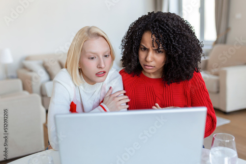 Two beautiful women using laptop for an online video call and online toasting with their friends. Online party for friends.