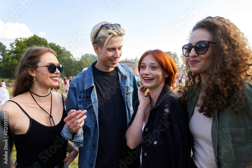 Group of young caucasian friends chatting and having fun on music festival