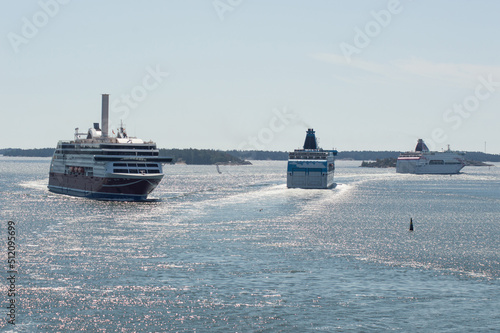 three ships in the Baltic sea. Blue water of the Stockholm fiord, blue sky with clouds