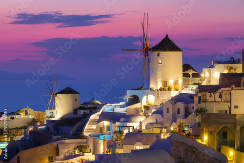 Oia village, Santorini, Greece. View of traditional houses in Santorini. Small narrow streets and rooftops of houses, churches and hotels. Landscape during sunset. Travel and vacation photography.