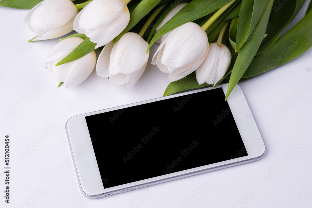 Bouquet of white tulips with blank screen mobile smartphone. Copy space for text. Bouquet of white tulips with blank screen mobile smartphone. Copy space for text.