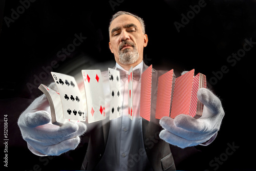 Magician with cards, Card manipulation, Croupier or casino dealer at gambling club or casino. Close up of male hand with with poker cards
