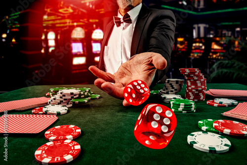 Gambling concept. Close up of male hand throwing dice at casino, gambling club. Сasino chips or Casino tokens, poker cards, gambling man spending time in games of chance photo