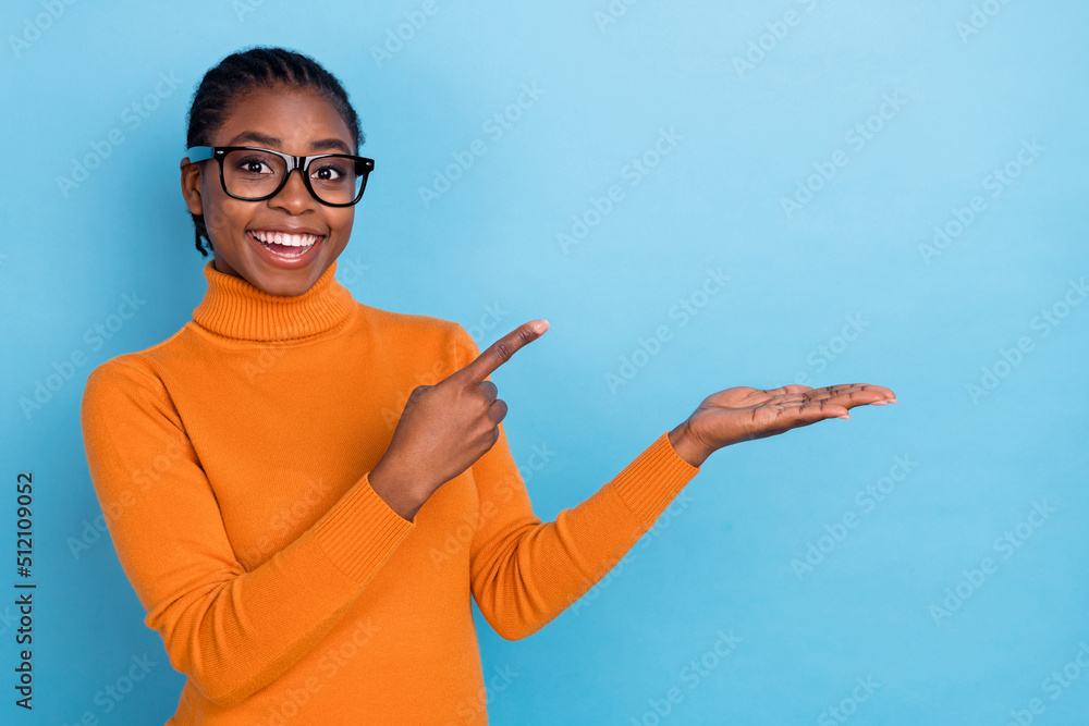 Portrait of attractive cheerful girl holding on palm demonstrating copy space ad look isolated over blue color background Portrait of attractive cheerful girl holding on palm demonstrating copy space ad look isolated over blue color background
