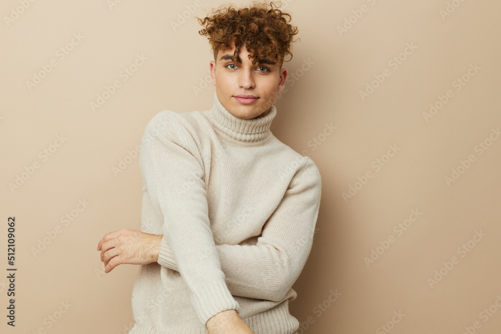 a handsome, attractive man stands on a beige background in stylish clothes and poses relaxed looking at the camera a handsome, attractive man stands on a beige background in stylish clothes and poses relaxed looking at the camera