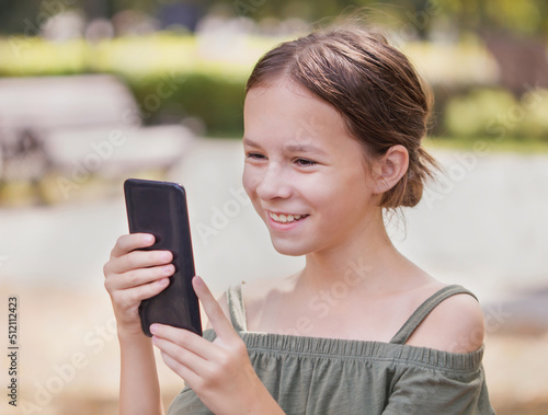 Happy girl talking on her phone. Pretty child surfing internet