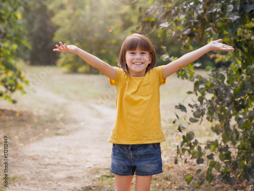 Young child arms raised up to sky, celebrating freedom. Positive children emotions. Free smiling girl in summer forest enjoying nature. Happy life concept