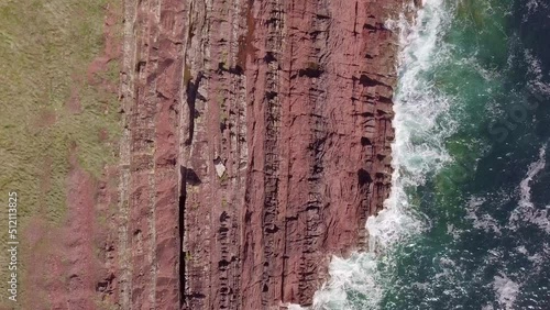 Drone overhead ariel footage of red cliffs and crashing waves photo