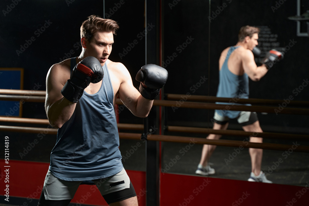 Determined sportsperson in boxing gloves practicing at gym Determined sportsperson in boxing gloves practicing at gym