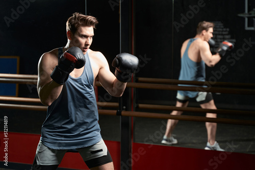 Determined sportsperson in boxing gloves practicing at gym