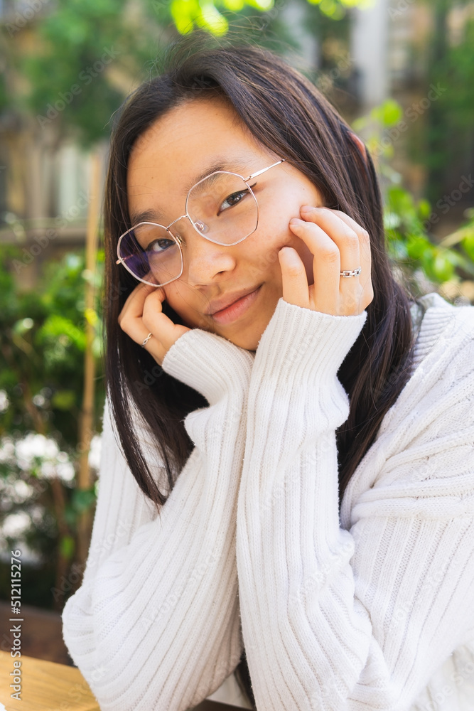 Asian woman in eyeglasses sitting on street