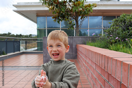 The blond boy with soapy hands narrowed his eyes and opened his mouth wide. Emotional five year old boy. photo