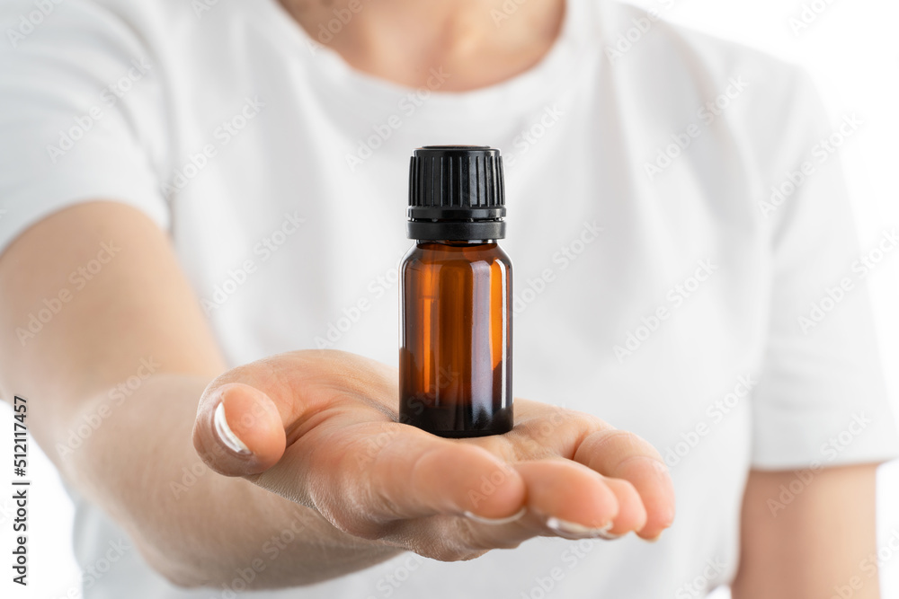 Close up photo of woman's hand holding a small jar of essential oils or another vitamins drops or supplements. Close up photo of woman's hand holding a small jar of essential oils or another vitamins drops or supplements.