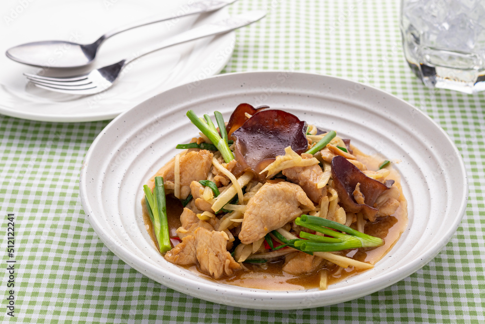 Stir-fried chicken with shredded gingers and wood ear mushrooms or gai pad khing served on a white serving plate. It is a popular Thai dish that does reflect Thai Chinese cuisine.