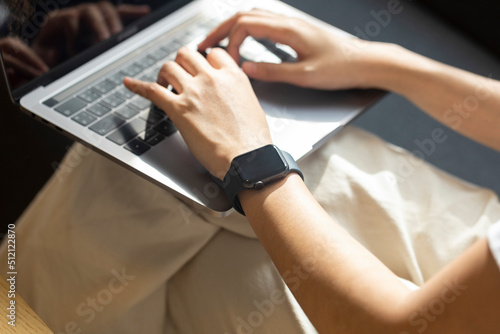 Close-up of the hands of a woman working from home with laptop and a smartwach.