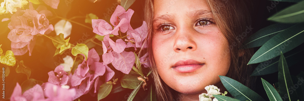 portrait face of candid beautiful little kid girl of eight years old on background of green plants and pink flowers during a summer vacation travel. gen z mental health concept. banner. flare