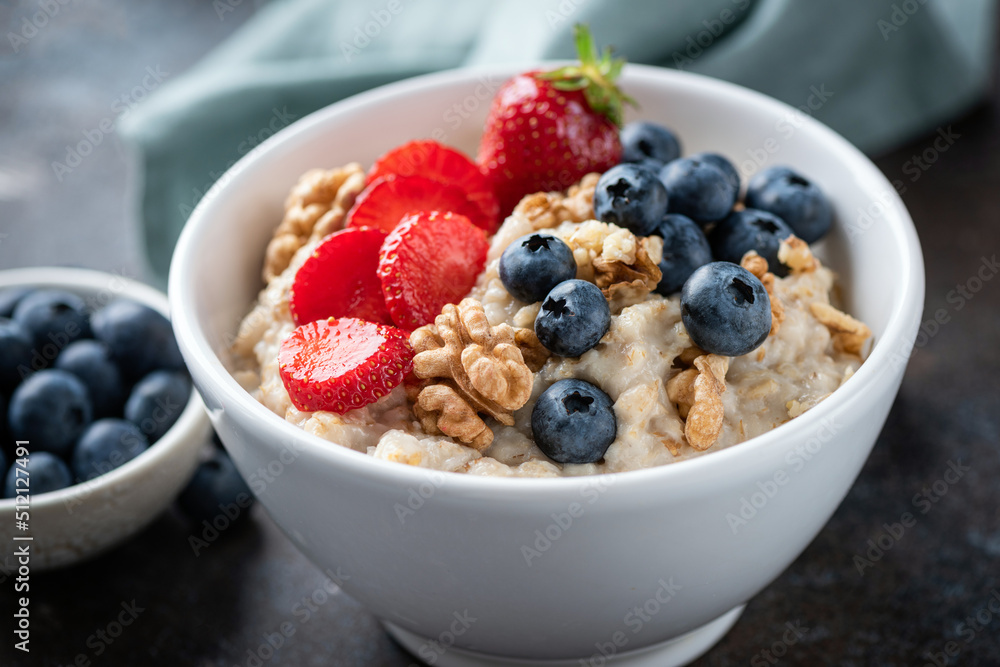 Oatmeal porridge bowl with blueberries, strawberries and nuts. Closeup view bowl of healthy breakfast oats Oatmeal porridge bowl with blueberries, strawberries and nuts. Closeup view bowl of healthy breakfast oats