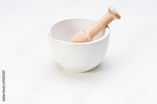 White ceramic mortar with a wooden pestle, isolated on white