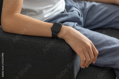 Close-up of man hand using his smartwatch and sitting on the couch while at home. © bennnn