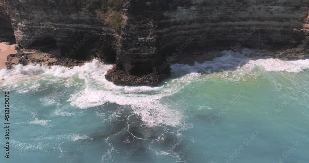 Wave is splashing on the rocky cliff on sunny day. Tsunami, power of water, power of ocean concept. Aerial view, drone shot Wave is splashing on the rocky cliff on sunny day. Tsunami, power of water, power of ocean concept. Aerial view, drone shot