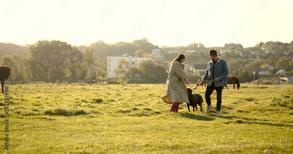 Young man in hat and young woman with dog in nature Young man in hat and young woman with dog in nature