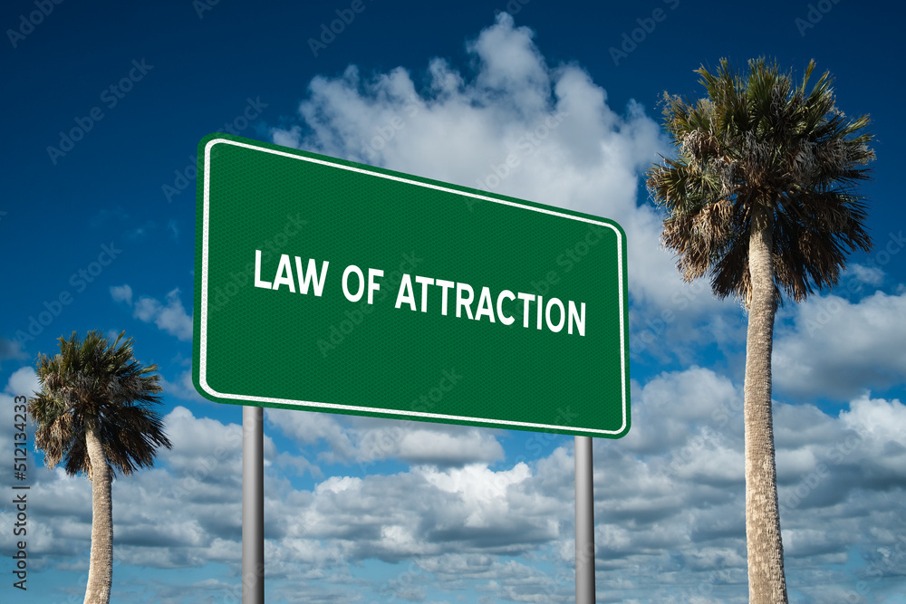 Fototapeta premium Highway sign with the words Law of Attraction on a beautiful blue sky background with palm trees. Motivational concept for finding what we want on the journey of life.