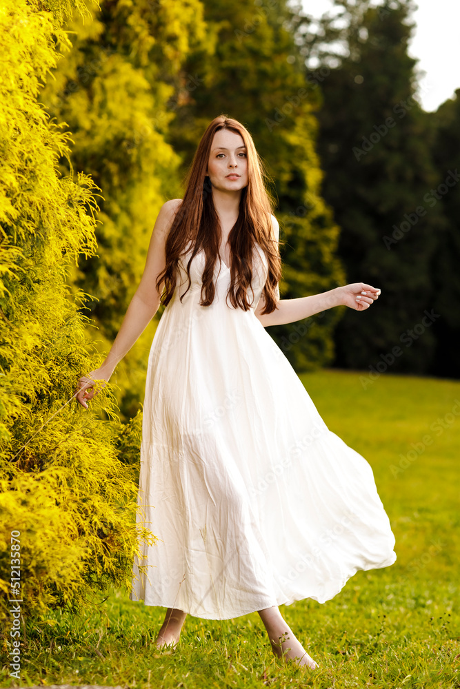 Ginger woman in white dress dancing at a park Ginger woman in white dress dancing at a park