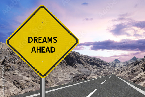 Yellow highway sign with the word Dreams and a metaphoric road leading to future success.