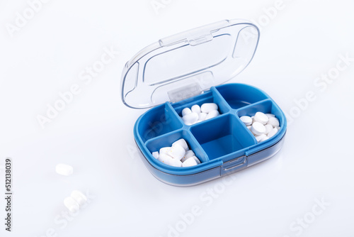 Pill box with colorful pills and vitamins. Plastic blue container with cells for medicines. Health concept. Selective focus, close-up.