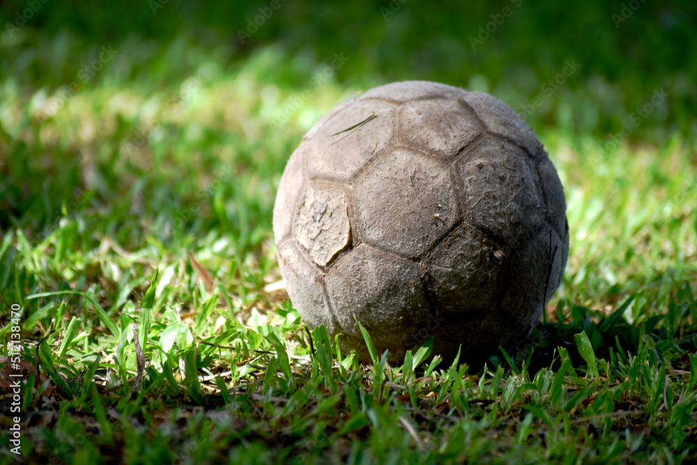 Fototapeta premium The old football was dark gray, laid on a green natural field.