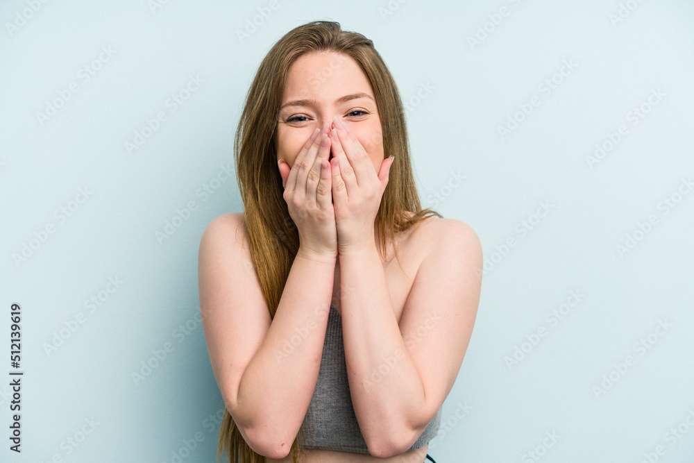 Young caucasian woman isolated on blue background laughing about something, covering mouth with hands.
