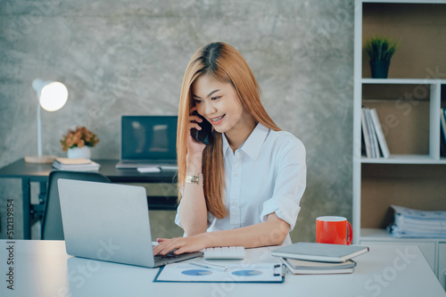Portrait of smiling pretty young business woman sitting on workplace