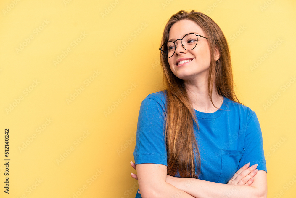 Young caucasian woman isolated on yellow background smiling confident with crossed arms.