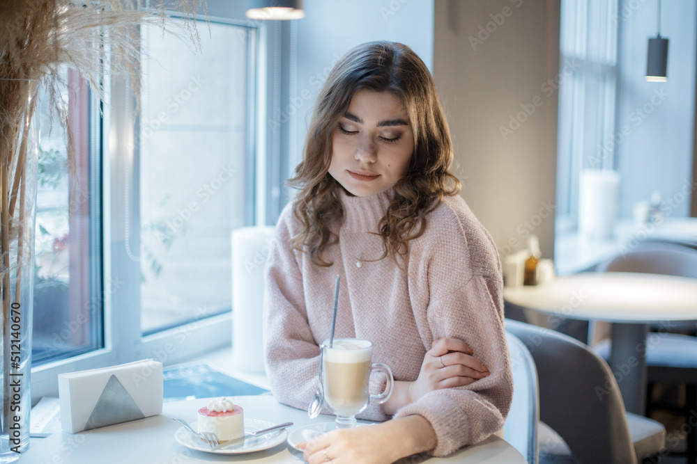 Young beautiful happy girl having Breakfast cappuccino and cake sitting in cafe. Young beautiful happy girl having Breakfast cappuccino and cake sitting in cafe.