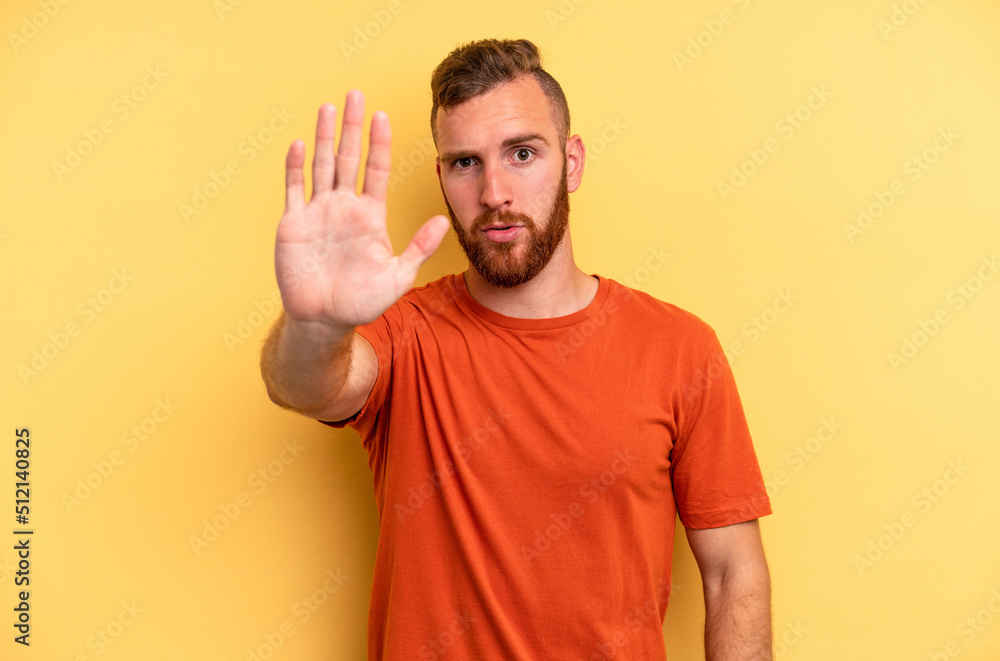 Young caucasian man isolated on yellow background standing with outstretched hand showing stop sign, preventing you. Young caucasian man isolated on yellow background standing with outstretched hand showing stop sign, preventing you.